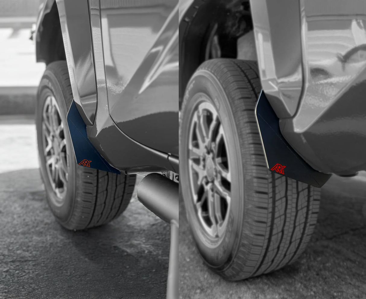 Close-up of a car's wheel arch with mud flaps on a road.