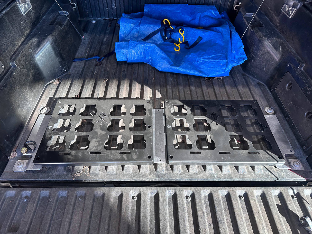 Trunk of a vehicle with a black cargo mat and blue tarp.
