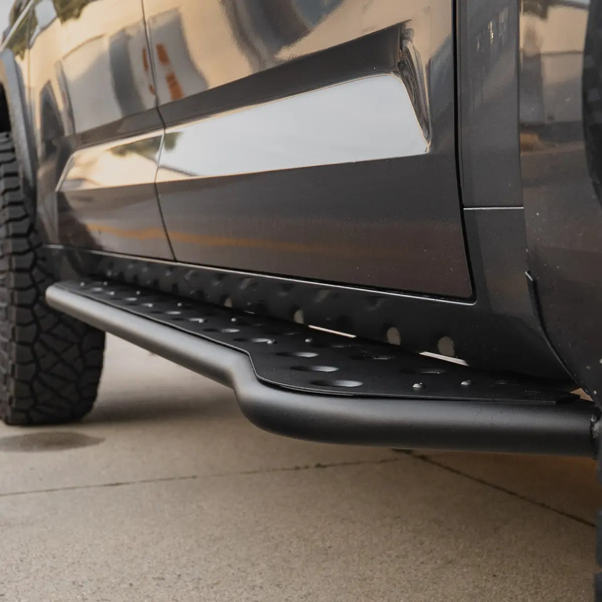 Close-up of a black vehicle's side step on a concrete surface