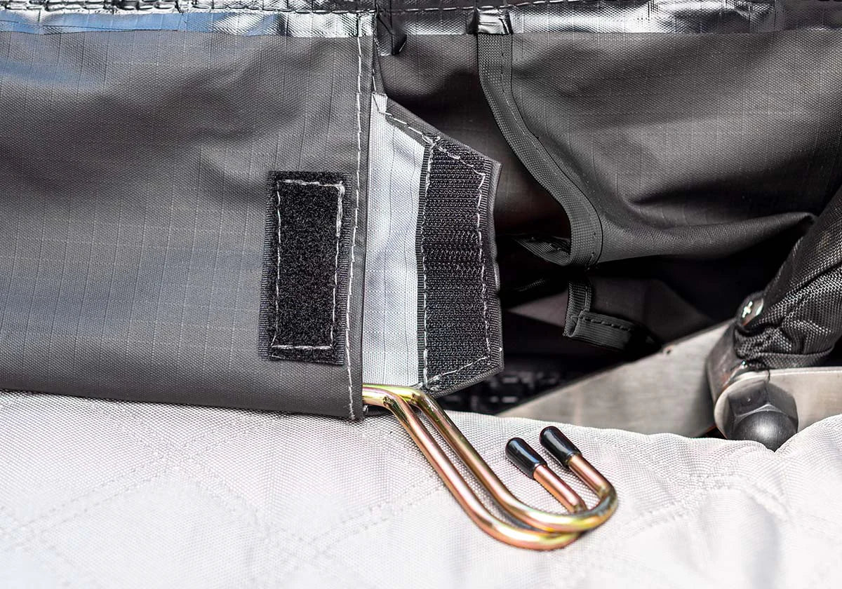 Close-up of a gray fabric with a gold tool and black strap on a white surface