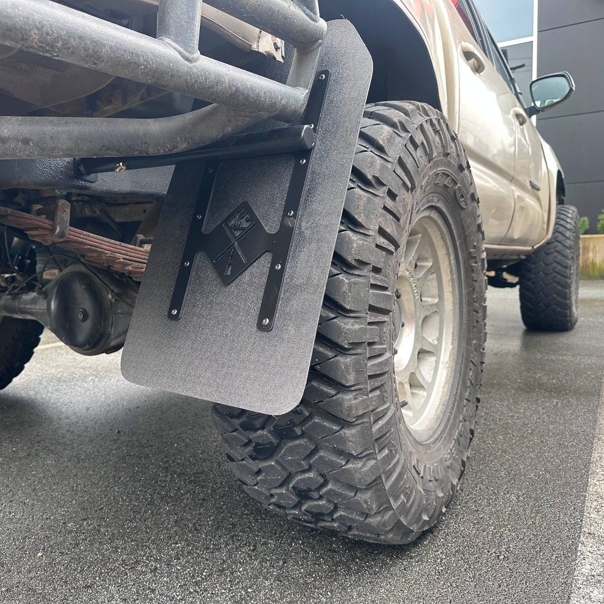 Close-up of a vehicle tire with a mud flap on a road
