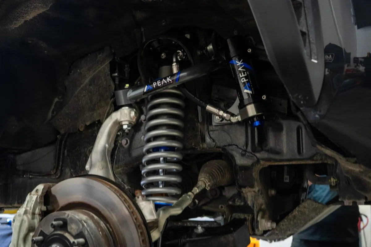 Close-up of a vehicle's suspension system with PEAK branding.
