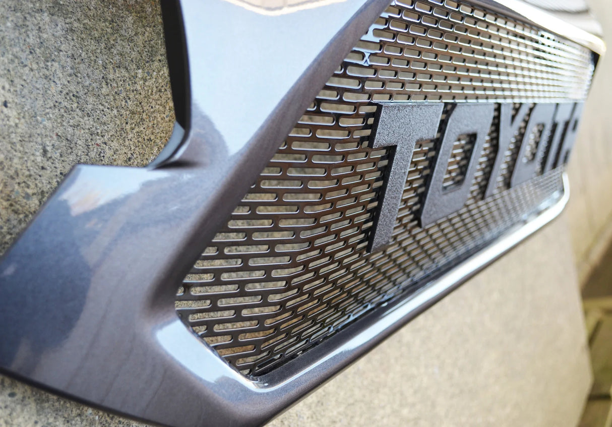 Close-up of a car grille with 'TOYOTA' branding on a textured surface.