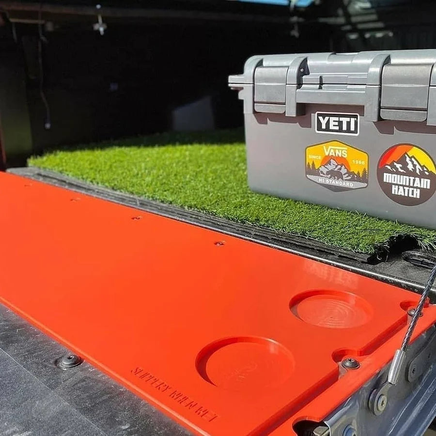 YETI cooler on a truck bed with grass mat and visible branding.