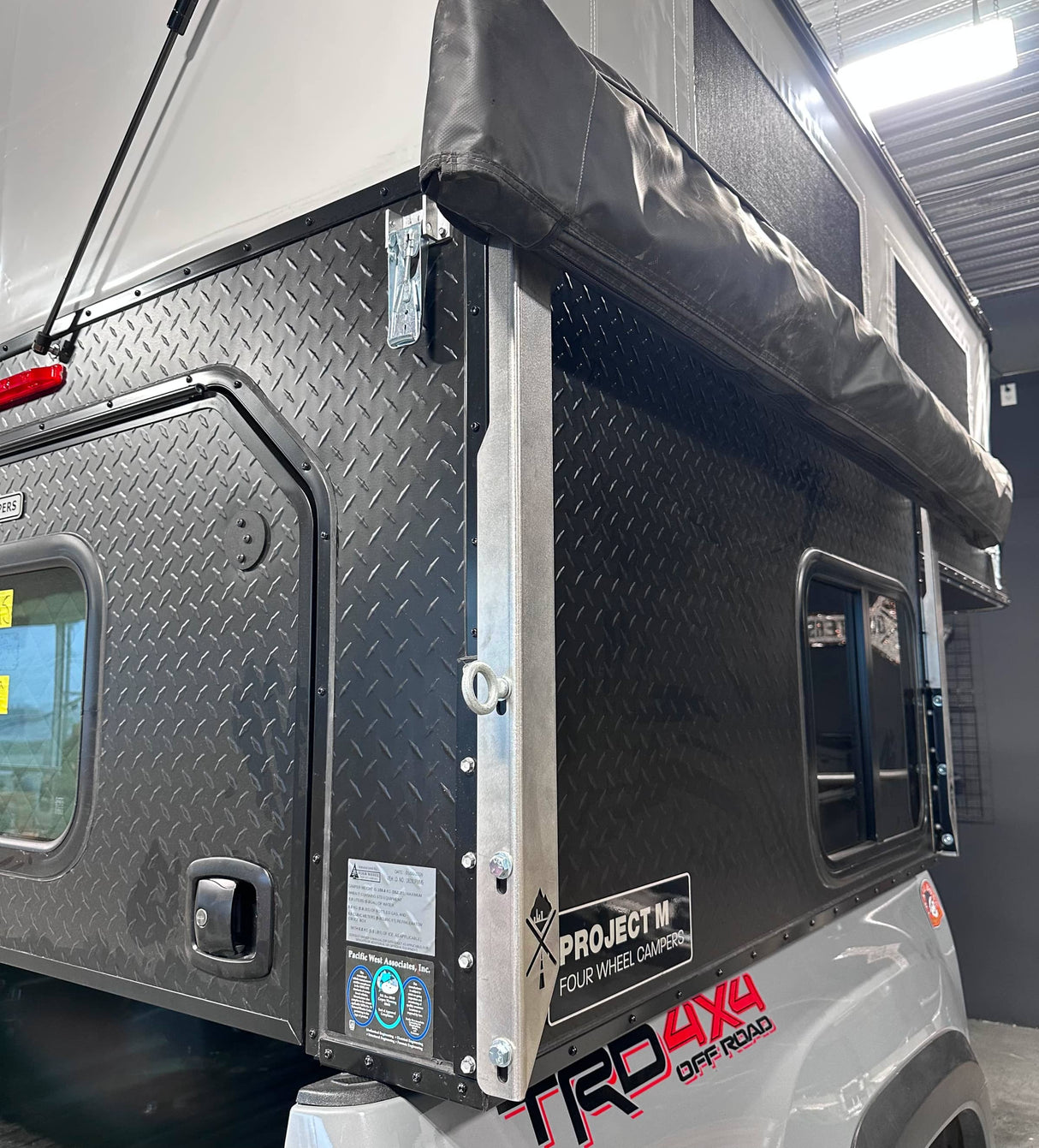 Metal awning bracket on black Project M camper