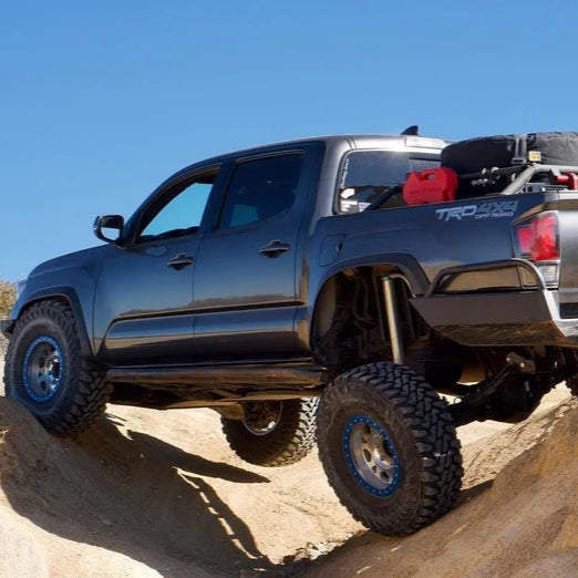 Black off-road truck with large tires rock crawling over rugged terrain