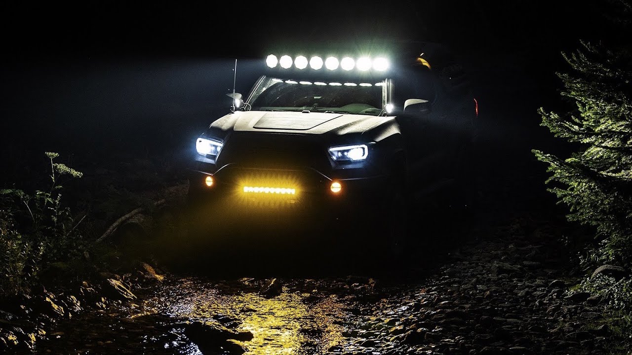 Truck on a trail with lights on at night time.