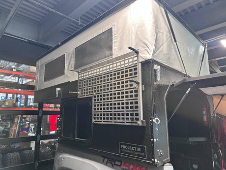 Back of a truck with a custom-built storage unit and 'Project M' branding.