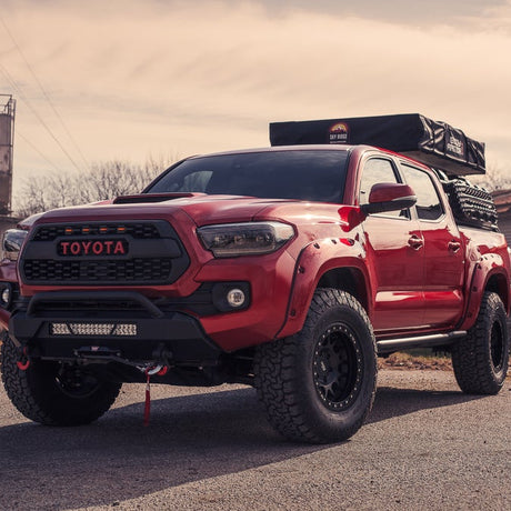Angled red Tacoma sits on pavement displaying 25 degree sliders bolted in place 