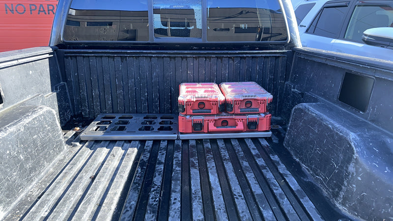 Truck bed with red coolers and a grill on a sunny day