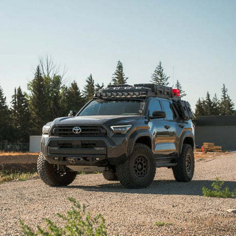 Toyota truck with off-road equipment on a gravel surface with trees in the background