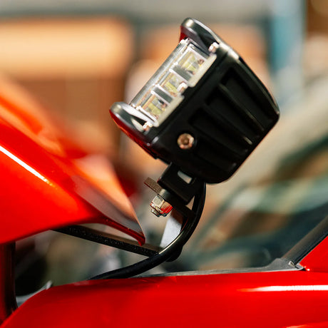 Close-up of a LED pod light on a red vehicle with a blurred background