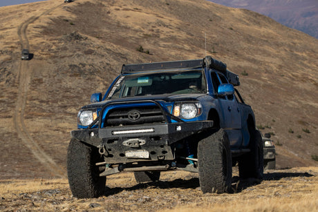 Blue Toyota truck on a dirt road with mountains in the background