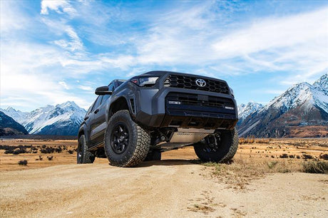Toyota truck on a dirt road with mountains in the background