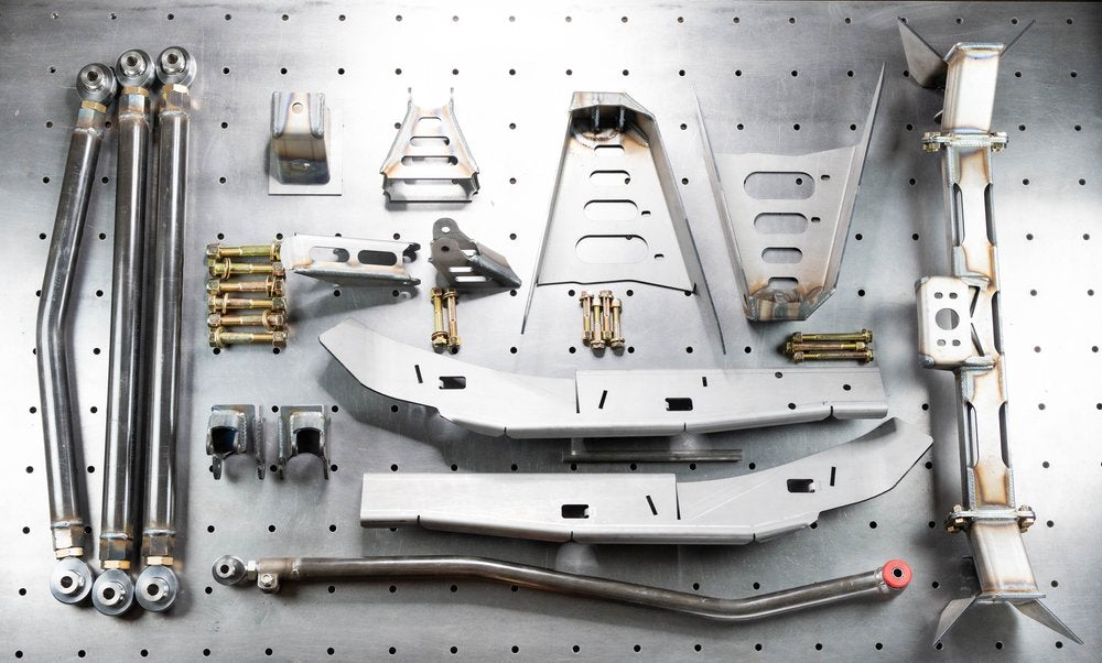 An array of metal suspension parts for a vehicle, including various brackets, tubing, and mounting hardware, displayed on a pegboard.