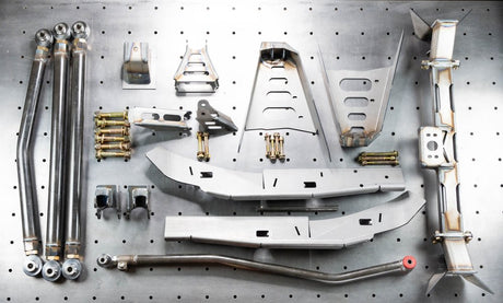 An array of metal suspension parts for a vehicle, including various brackets, tubing, and mounting hardware, displayed on a pegboard.