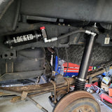 Close-up of a vehicle suspension system with a 'LOCKED' label on a workshop background.