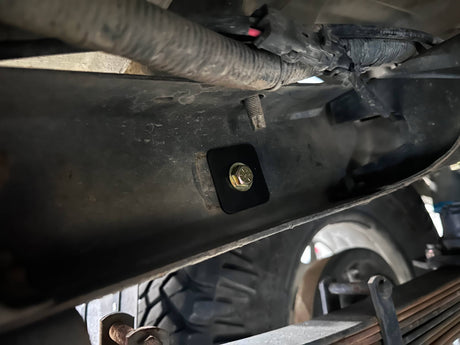 Close-up of a vehicle's undercarriage with a bolt and surrounding components.