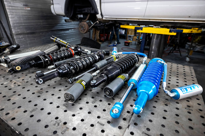 Collection of shock absorbers on a metal workbench in a garage setting