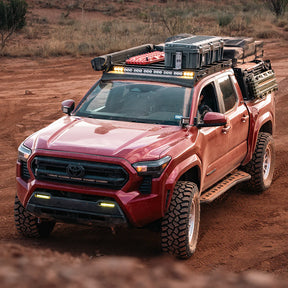 Red Toyota truck with off-road equipment on a dirt road