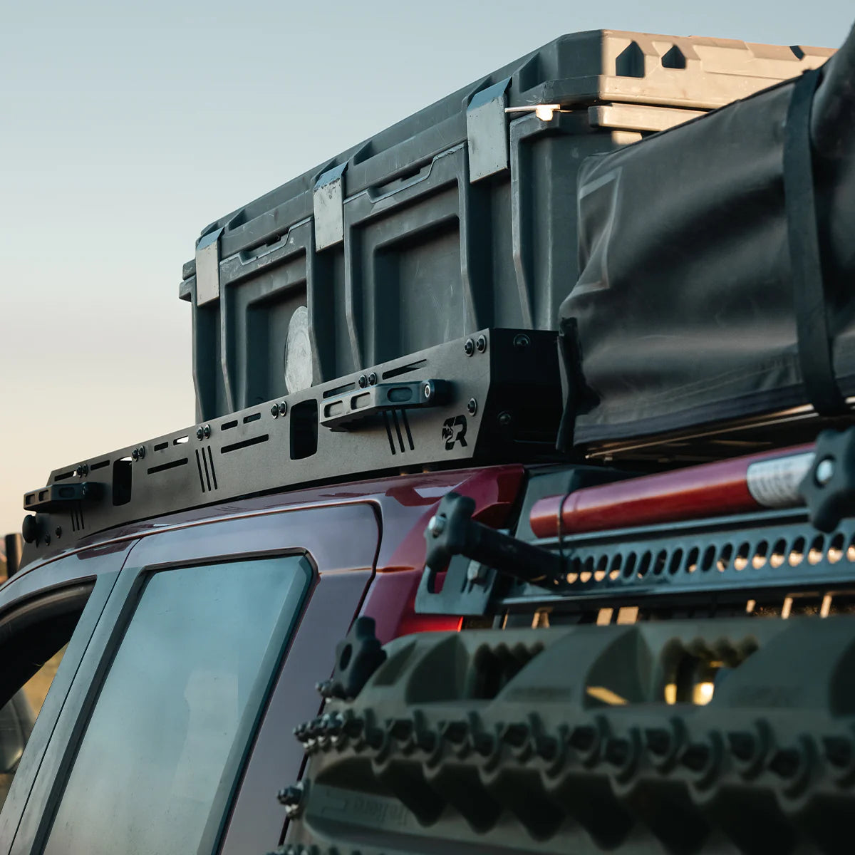 Roof rack system on a vehicle with storage boxes attached against a clear sky.