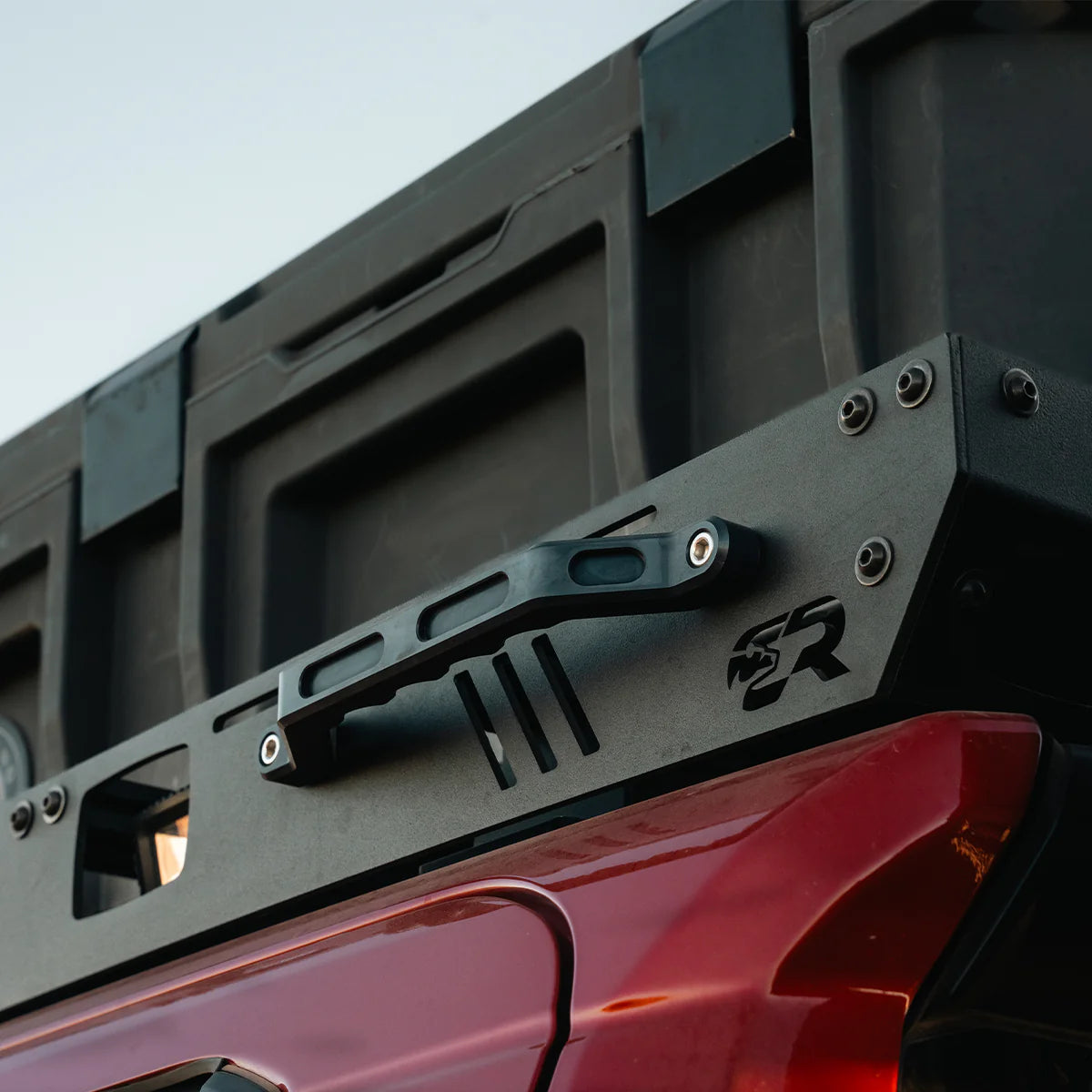 Close-up of a vehicle roof rack system on a red vehicle with a clear sky background.