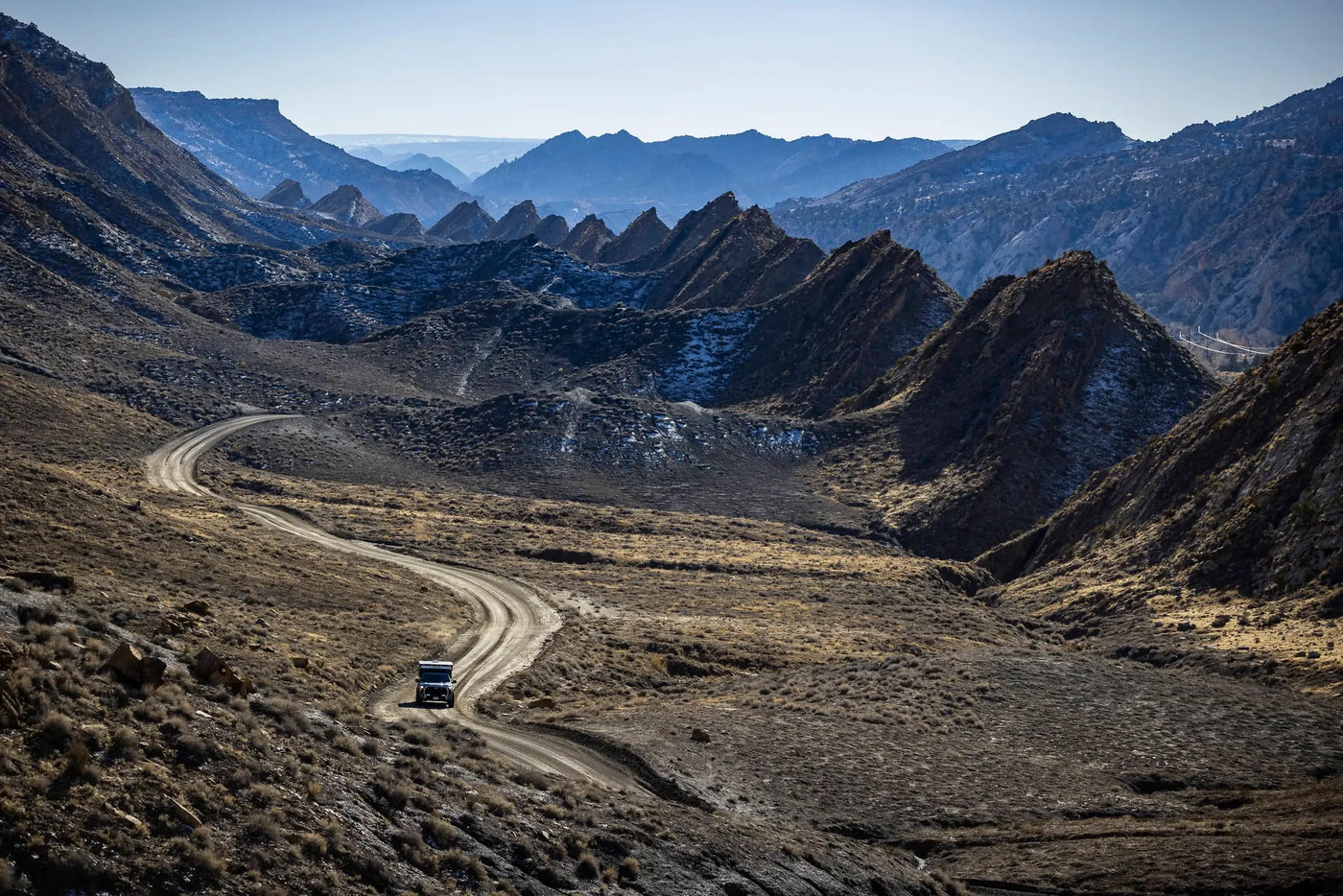 An overland equipped truck driving off road with a mountain range in the background.