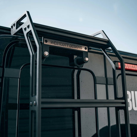 Black vehicle roof rack with 'Westcott Designs' branding against a clear sky.