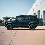 Black off-road vehicle parked on a concrete surface with a building in the background