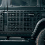 Close-up of a black vehicle side panel featuring a large black metal grid protective grille or guard over the door and side area, with part of the tire and dark body visible.