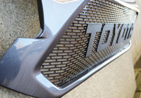 Close-up of a car grille with 'TOYOTA' branding on a textured surface.