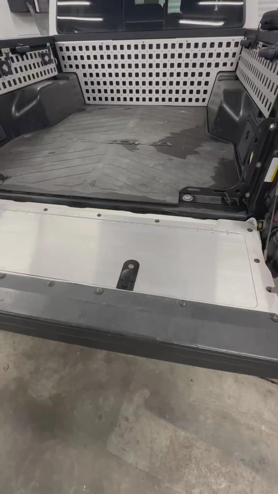 Open truck bed with a checkered floor and tools on a concrete surface