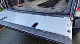 Truck bed with a metal floor panel and tools on a concrete surface