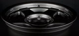 Face 2. Close-up of a black alloy wheel on a dark background