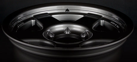 Face 2. Close-up of a black alloy wheel on a dark background