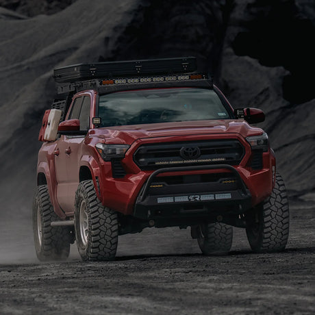 Red Tacoma driving on dirt road with Stealth Bumper
