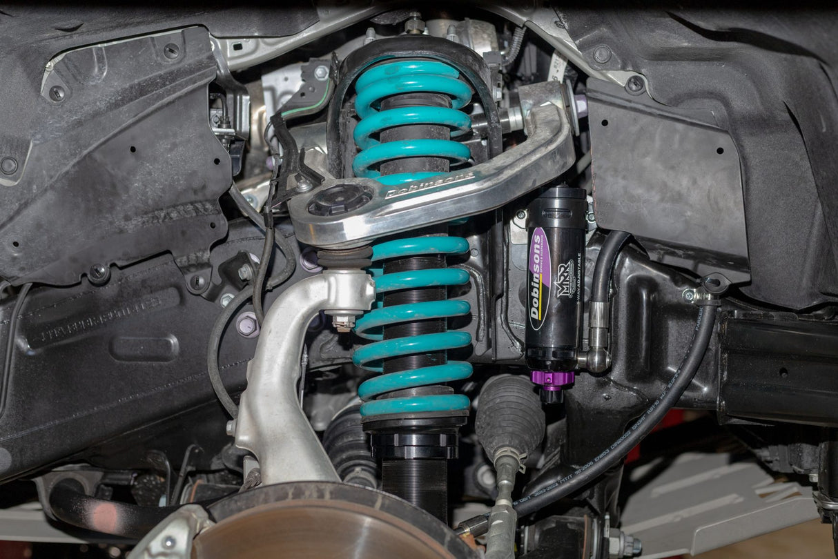 Close-up of a car suspension system with green shock absorbers.