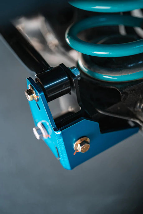 Close-up of a blue suspension control valve with coiled spring on a blurred background