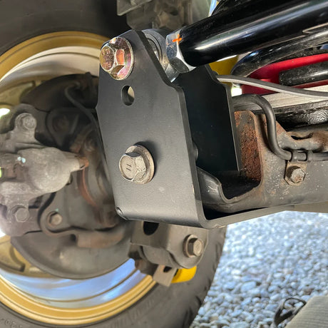 Close-up of a motorcycle suspension system with visible rust and wear.