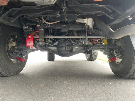 Close-up of a vehicle's undercarriage with suspension components on a road.