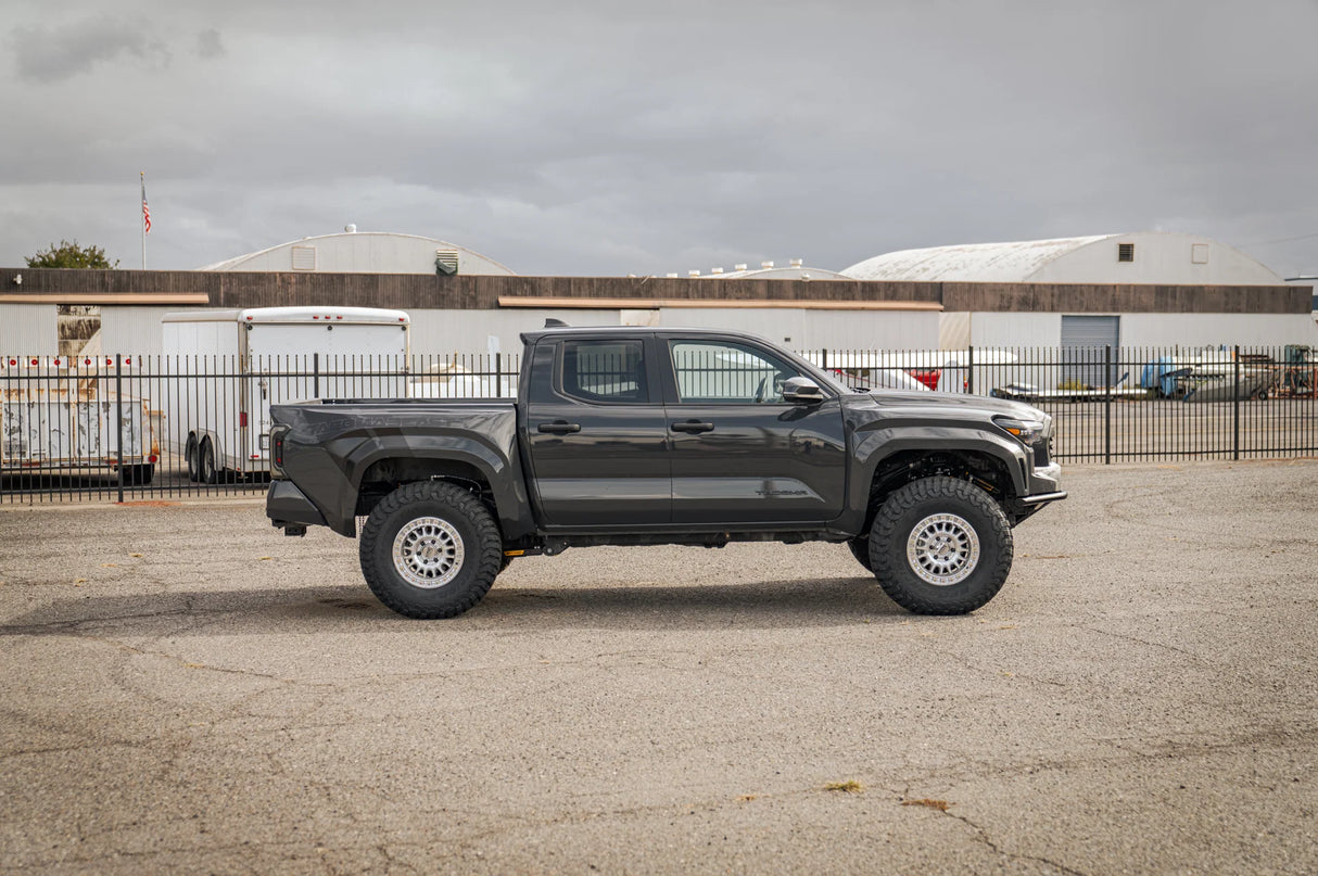 Gray pickup truck parked on a concrete surface with industrial buildings in the background