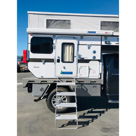 Camper van with a ladder leading to the door on a clear day.