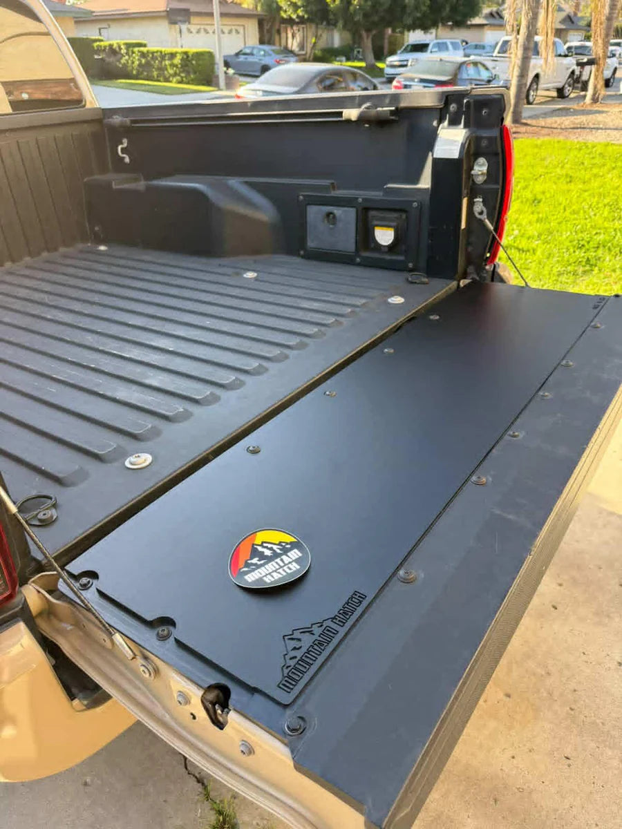 Truck bed with a black cover and a logo on a residential street.