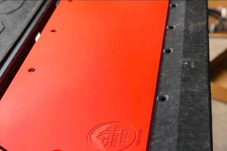 An orange plastic tailgate insert for a Toyota Tacoma, displayed in an installed position on the truck's bed.