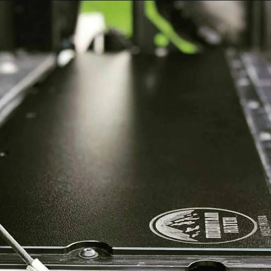A black plastic tailgate insert for a Toyota Tacoma, displayed in an installed position on the truck's bed.