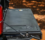 A black plastic tailgate insert for a Toyota Tacoma, displayed in an installed position on the truck's bed.