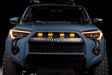 Front view of a Toyota vehicle with illuminated headlights on a black background