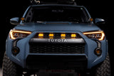 Front view of a Toyota vehicle with illuminated headlights on a black background