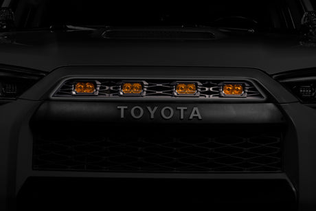 Close-up of a Toyota vehicle grille with orange lights on a dark background