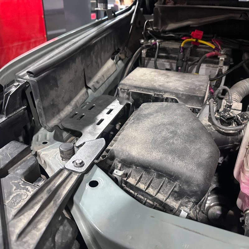 Car engine compartment with visible components and wiring.